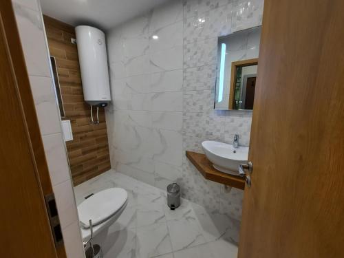 a white bathroom with a toilet and a sink at Апартамент Тилия in Gabrovo