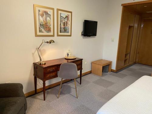 a bedroom with a desk with a lamp and a bed at Quinta do Paço Hotel in Vila Real