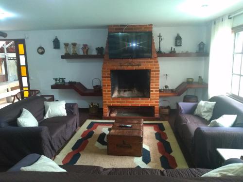 a living room with two couches and a fireplace at Casa com Piscina e Churrasqueira Perto da CBF, Feirarte, Parque Nacional in Teresópolis