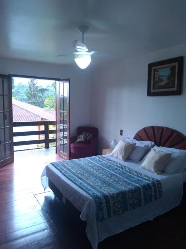 um quarto com uma cama e uma porta de vidro deslizante em Casa com Piscina e Churrasqueira Perto da CBF, Feirarte, Parque Nacional em Teresópolis