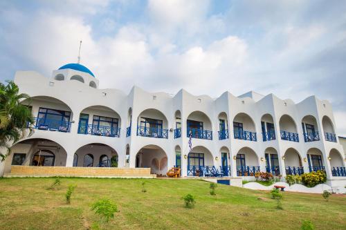 a white building with blue balconies and a palm tree at 地中海海景包棟-無邊際泳池 家庭出遊 朋友聚會 生態體驗 推薦包棟首選 in Xiaoliuqiu