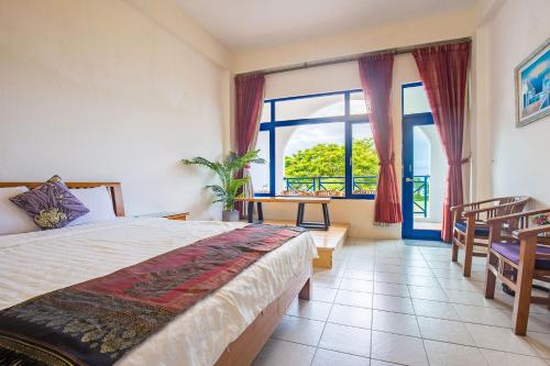 a bedroom with a bed and a large window at 地中海海景包棟-無邊際泳池 家庭出遊 朋友聚會 生態體驗 推薦包棟首選 in Xiaoliuqiu