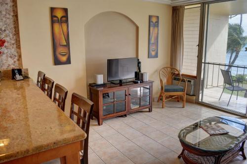 a living room with a television and a table at Hale Kai O'Kihei 302 in Kihei