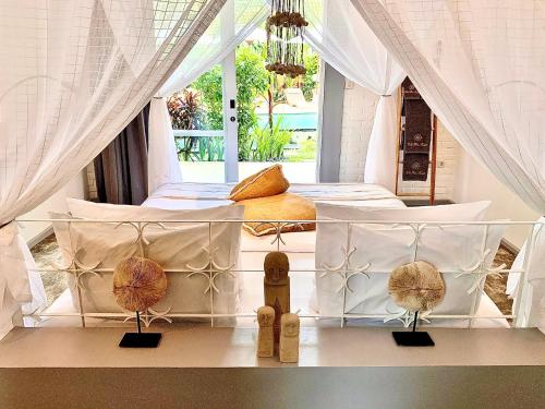 a bedroom with a white bed with white curtains at Hari Indah Boutique Hotel & Spa in Uluwatu