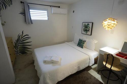 a white bedroom with two beds and a desk at Casa Coral in Luquillo