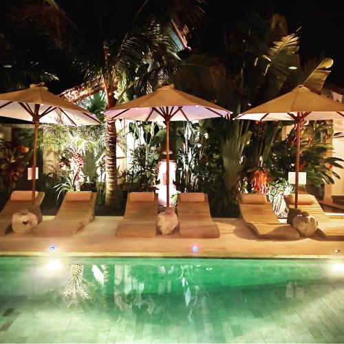 a swimming pool with umbrellas and chairs and a swimming pool at Hari Indah Boutique Hotel & Spa in Uluwatu