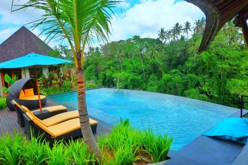 un complejo con una piscina con sillas y una palmera en Kadewa Retreat Ubud - Adults Only, en Ubud