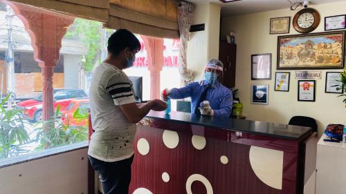 a man wearing a mask standing at a bar at Hotel Muskan Palace in Jaipur