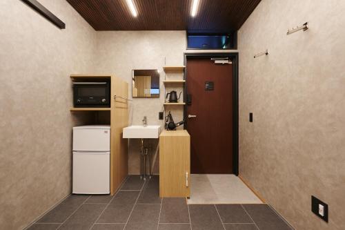 Zimmer mit einem Bad mit einem Waschbecken und einer Tür in der Unterkunft Colors Hakata in Fukuoka