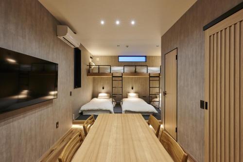 Zimmer mit 2 Betten und einem Tisch mit einem TV in der Unterkunft Colors Hakata in Fukuoka