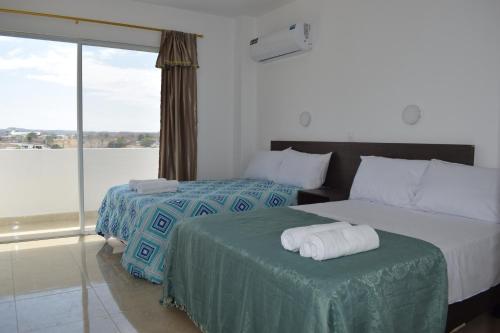 a hotel room with two beds and a large window at Mare S&M Casa Hostal in Manta