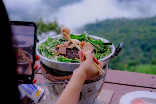 a person taking a picture of a bowl of food at ภูน้ำทิพย์ รีสอร์ท in Ban Huai Phai
