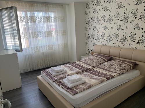 1 cama en un dormitorio con una pared con flores en Stefanos Apartament, en Baia Mare