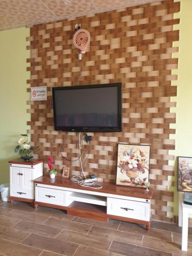 ein Wohnzimmer mit einem TV an einer Backsteinwand in der Unterkunft استراحة البيت الريفي in Umm Lajj