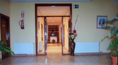 un couloir avec une porte et un vase de fleurs dans l'établissement HOTEL RURAL HIDALGO, à Torreperogil