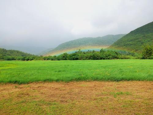 a field of green grass with mountains in the background at 樂逃園 Leto Retreat 屏東滿州包棟民宿 in Manzhou