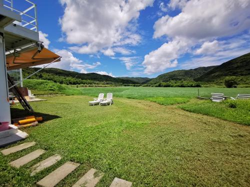 a group of white chairs sitting on a grass field at 樂逃園 Leto Retreat 屏東滿州包棟民宿 in Manzhou