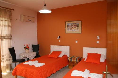2 camas en una habitación con paredes de color naranja en Stergia Apartments, en Kardamaina