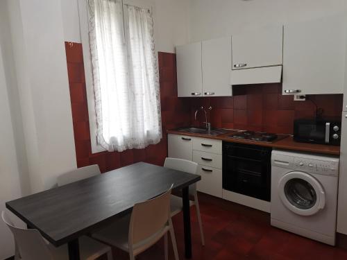 a kitchen with a table and a washing machine at RES Clara in Padova