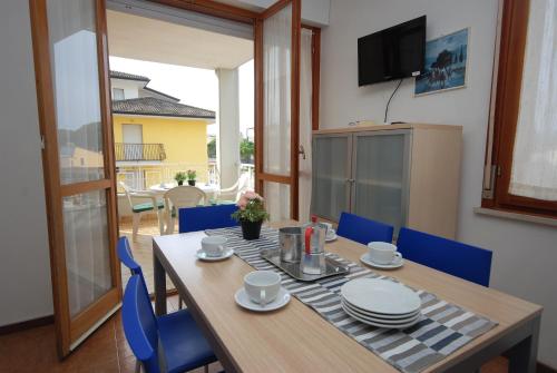 a dining room table with blue chairs and a television at Residenza Gardenia in Lignano Sabbiadoro