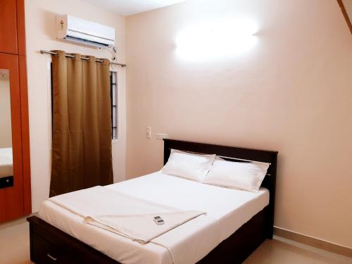 a small bedroom with a bed with white sheets at Chippy Apartments No23 in Chennai