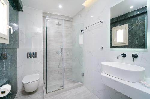 a white bathroom with a shower and a sink at Foti's Villas in Skala Potamias