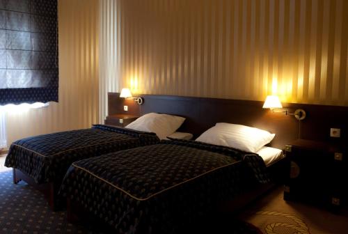 two beds in a hotel room with two lamps at Shuma in Dąbrowa Górnicza
