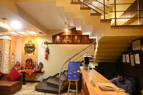 a man sitting at a counter in a room with a staircase at Hotel Heritage Inn at Assi Ghat in Varanasi
