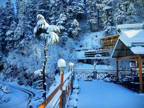 einen schneebedeckten Hof mit einem Haus und Bäumen in der Unterkunft Soham's Chateau De Naggar - Manali in Nagar