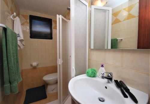 bagno con lavandino, servizi igienici e specchio di Villa Tiziano a Lignano Sabbiadoro