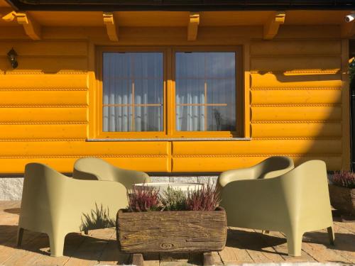 a group of chairs and a table in front of a building at Apartamenty Liliowe SPA & Wellness in Murzasichle