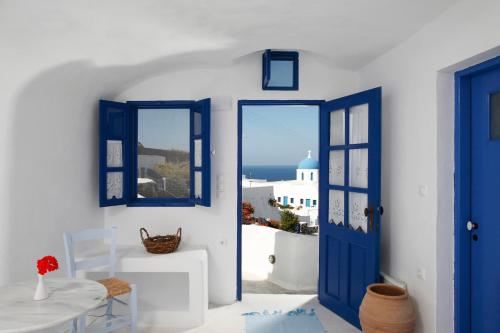 a blue door in a white room with a table at Aghios Artemios Traditional Houses in Imerovigli