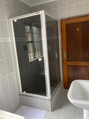 a glass shower in a bathroom with a sink at Marion Lodge in Johannesburg
