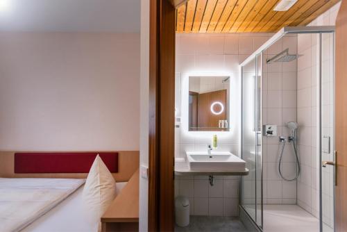 La salle de bains est pourvue d'un lavabo et d'une douche avec un lavabo. dans l'établissement Hotel Phönix, à Rastatt