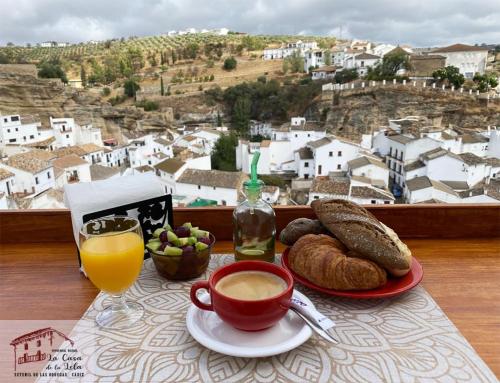 ein Tisch mit einer Tasse Kaffee und einem Teller Brot in der Unterkunft La Casa de la Lela in Setenil de las Bodegas