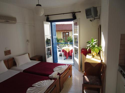 a bedroom with two beds and a door to a patio at Hotel Mariona in Pythagoreio