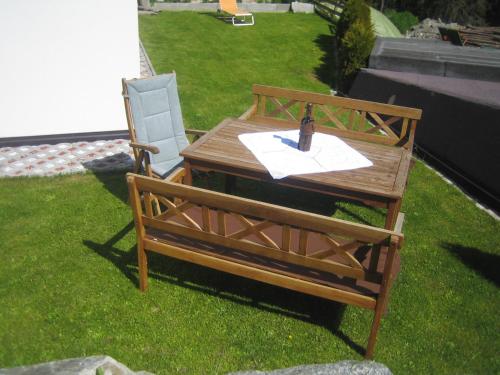 a wooden table and a chair on the grass at Apart Raphael in Niederthai