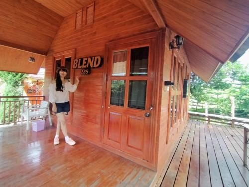 a woman standing on the porch of a wooden building at ภูน้ำทิพย์ รีสอร์ท in Ban Huai Phai