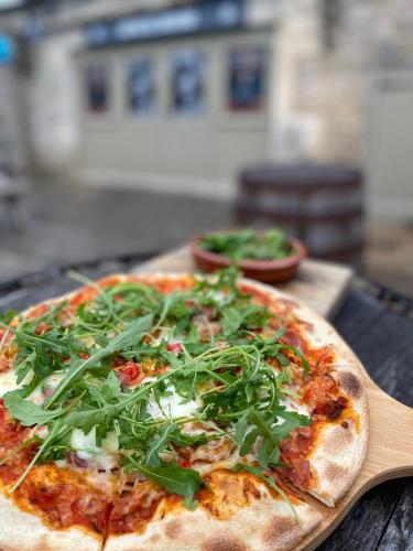a pizza with greens on it sitting on a table at THE RED LION in Cricklade