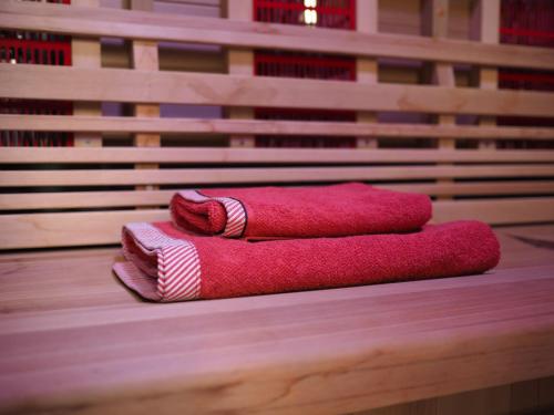 dwa czerwone ręczniki siedzące na drewnianej ławce w obiekcie Au jardin des Vennes w mieście Liège