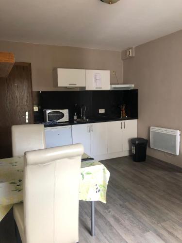 une cuisine avec des armoires blanches et une table et des chaises dans l'établissement Appartement à l'ange, à Climbach