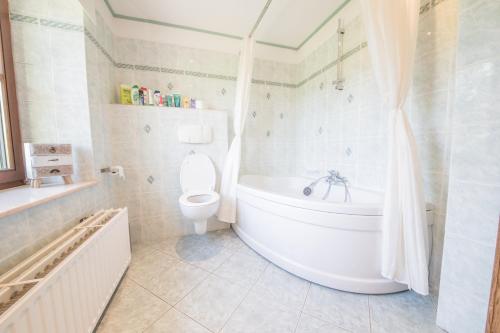 a white bathroom with a tub and a toilet at Le Longueville in Durbuy