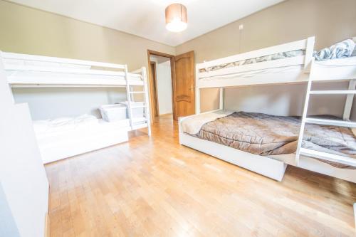 a bedroom with white bunk beds and a hardwood floor at Le Longueville in Durbuy