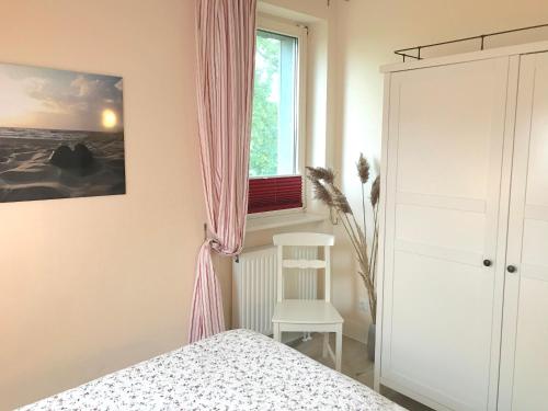 a bedroom with a bed and a window and a chair at Ferienwohnungen im Haus Borée in Prerow