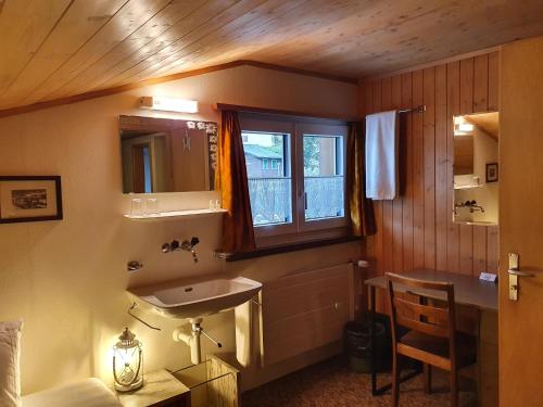 ein Bad mit einem Waschbecken und einem Fenster in der Unterkunft Hotel Restaurant Bergheim in Flumserberg