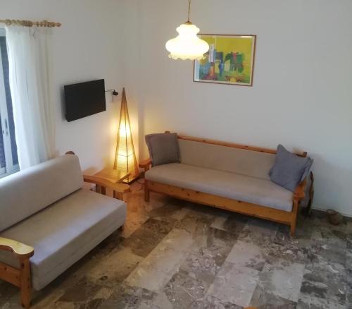 a living room with two couches and a tv at Perigiali beach apartment - 2 free bikes in Periyiálion