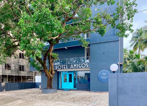 a blue building with a tree in front of it at Amigos Candolim Beach in Candolim