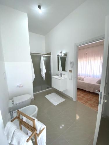 a bathroom with a toilet and a sink and a bed at Le Fresie B&B in SantʼAntìoco