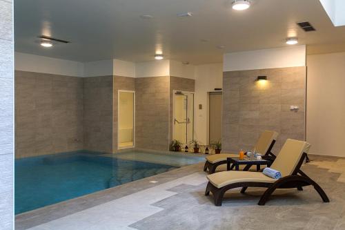 a swimming pool with two chairs and a table in a room at Hotel Manora in Nerezine