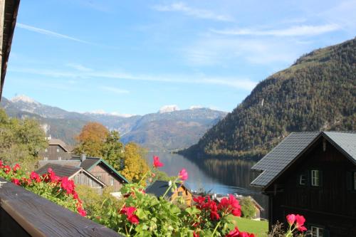 a view of a lake and mountains with red flowers at Ferienwohnung Syen in Grundlsee